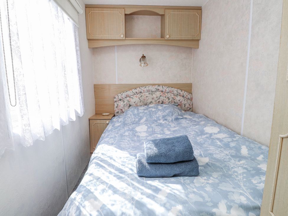 A bedroom with a bed and towels at Fron Dderw Caravan Llanfairynghornwy near Llanfechell