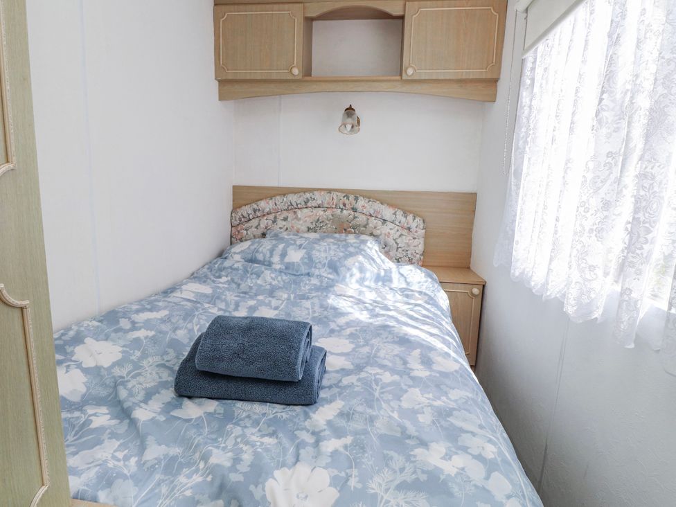 A bedroom with a bed and a bedside table at Fron Dderw Caravan near Llanfairynghornwy
