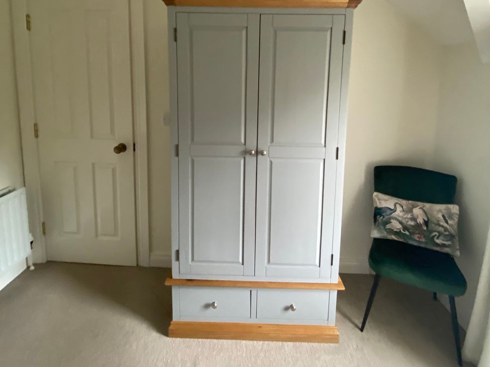 A wardrobe and chair in a bedroom at 4 The Cloisters, Bushmills, County Antrim
