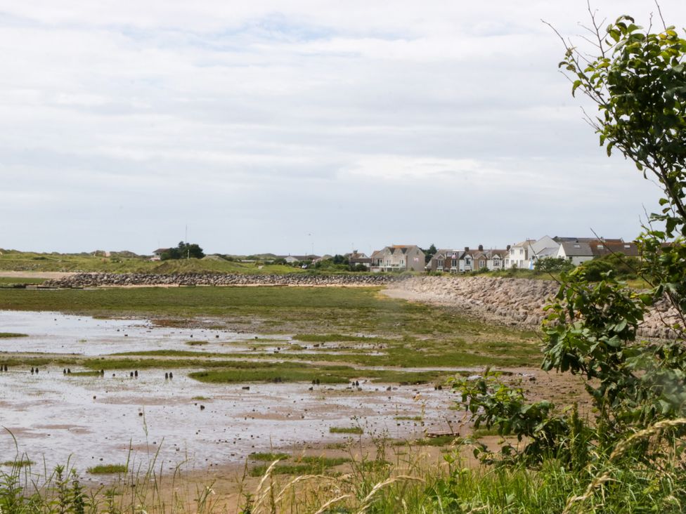 A view of houses by a shore with grass and water at Harbour Retreat in Haverigg