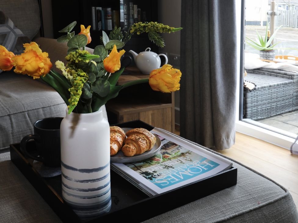 A living room with a vase of flowers and croissants on a tray at Apartment 3 in Trearddur Bay