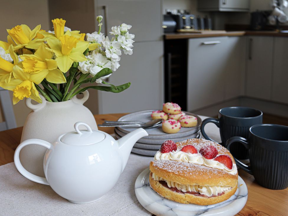 A kitchen table with tea set and cake at Apartment 3 Trearddur Bay