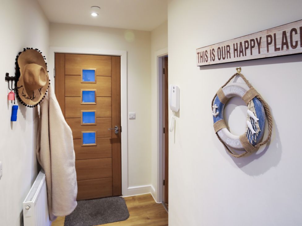 A hallway with a door and coat hooks at Apartment 3 Trearddur Bay