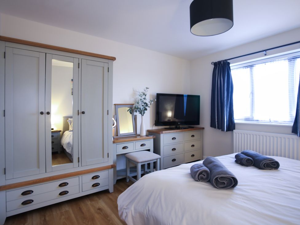 A bedroom with a bed, wardrobe, and television at Apartment 3 in Trearddur Bay