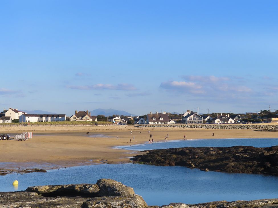 A beach with people walking near water at Apartment 3 Trearddur Bay