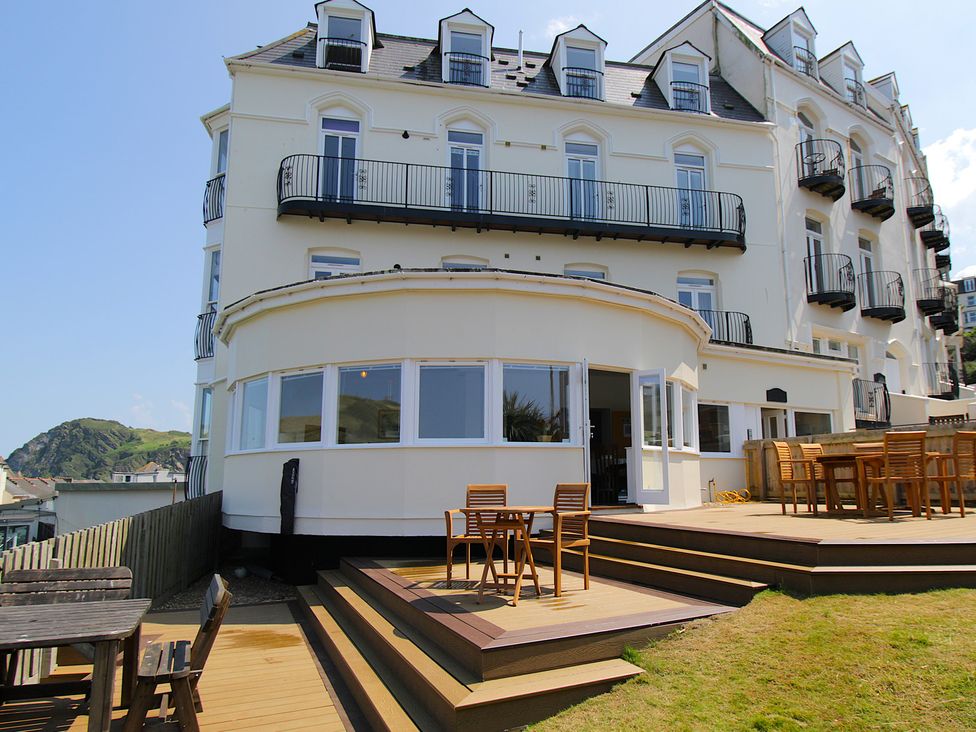An outdoor area with wooden deck and tables at 11 Cove View Apartments Ilfracombe