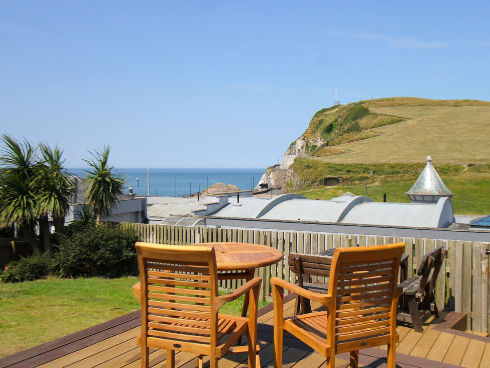 A wooden table and chairs overlooking the sea at 11 Cove View Apartments Ilfracombe