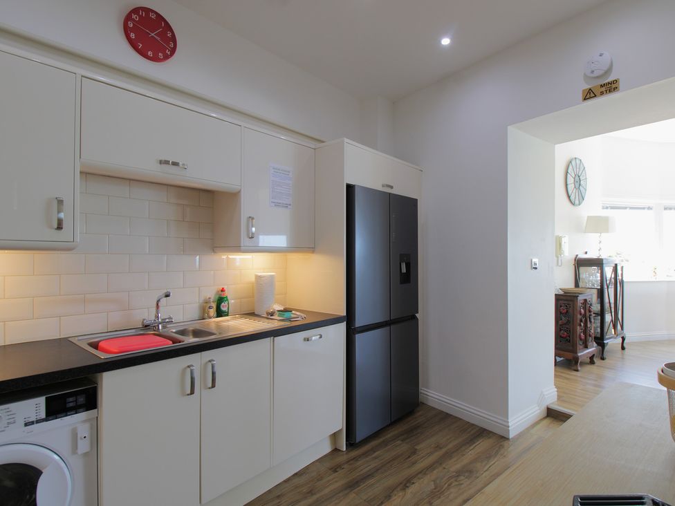 A kitchen with cabinets, sink, refrigerator and washing machine at 11 Cove View Apartments Ilfracombe