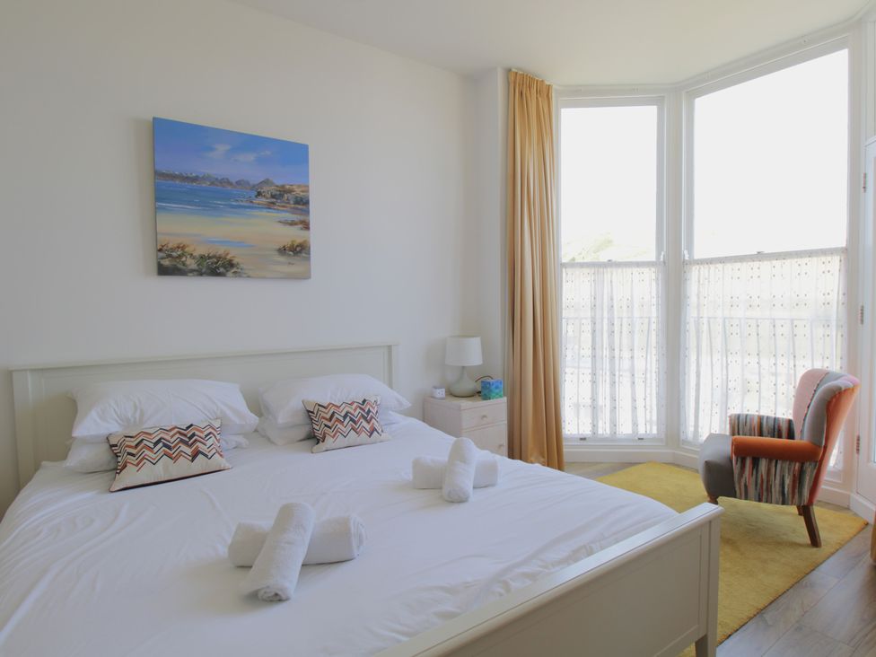 A bedroom with a bed and chair at 11 Cove View Apartments in Ilfracombe