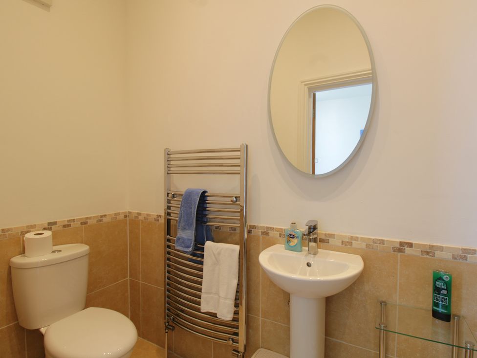 A bathroom with a toilet, a sink, and a mirror at 11 Cove View Apartments in Ilfracombe