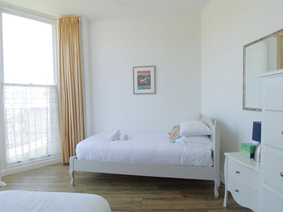 A bedroom with a bed and dresser at 11 Cove View Apartments Ilfracombe