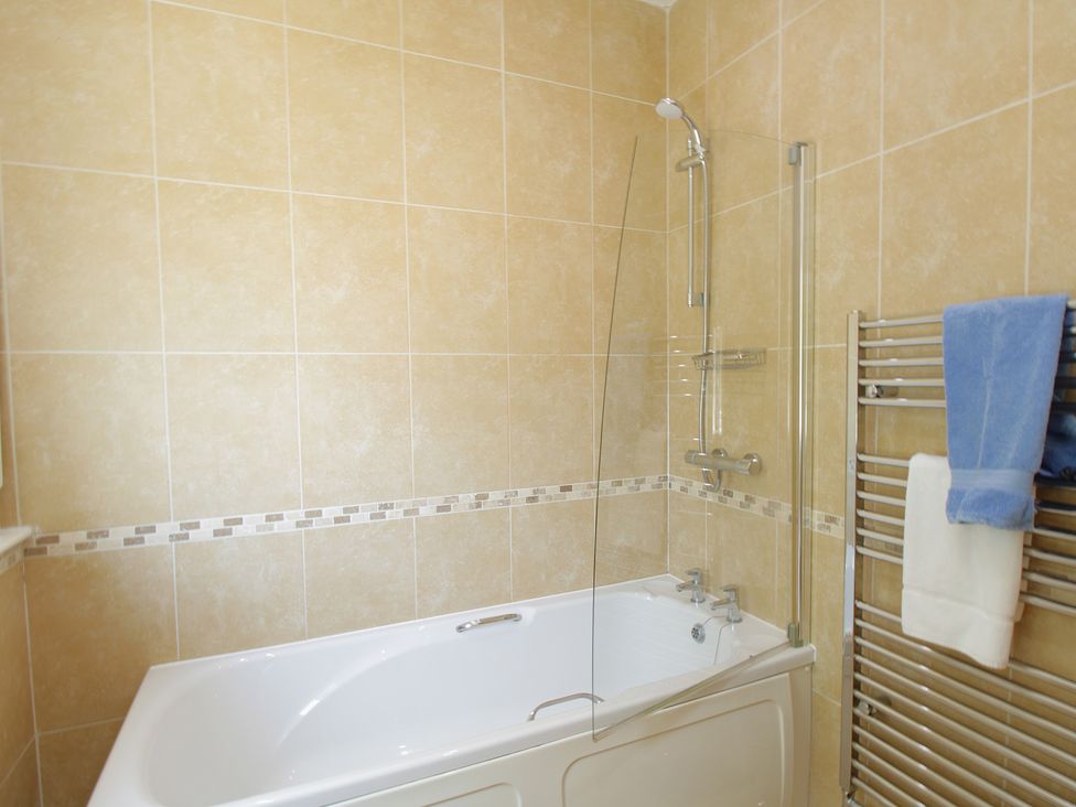 A bathroom with a bathtub and shower fixtures at 11 Cove View Apartments Ilfracombe