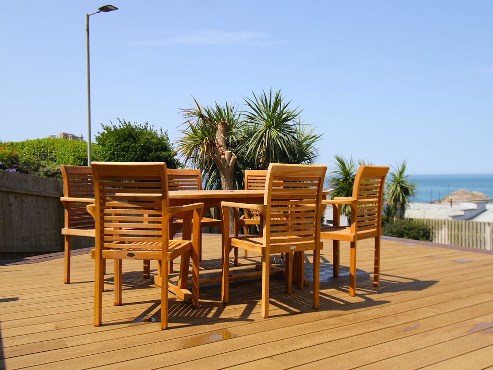 A dining table with wooden chairs on a deck at 11 Cove View Apartments Ilfracombe