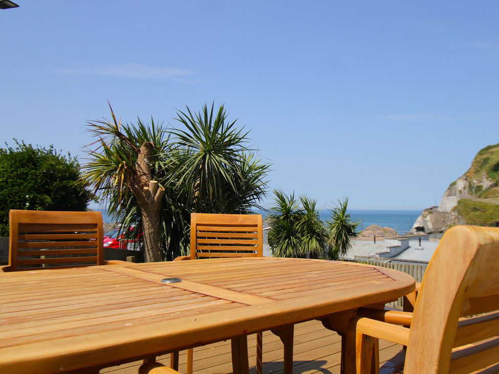 A wooden table with chairs and a view of the ocean at 11 Cove View Apartments Ilfracombe