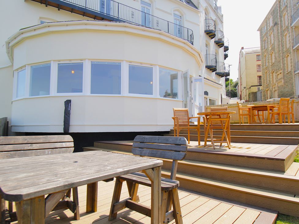 An outdoor area with wooden tables and chairs at 11 Cove View Apartments Ilfracombe