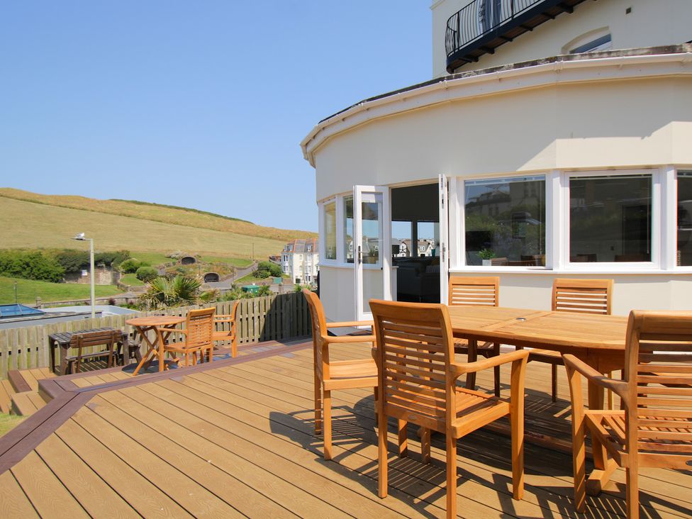 An outdoor seating area with wooden furniture at 11 Cove View Apartments in Ilfracombe