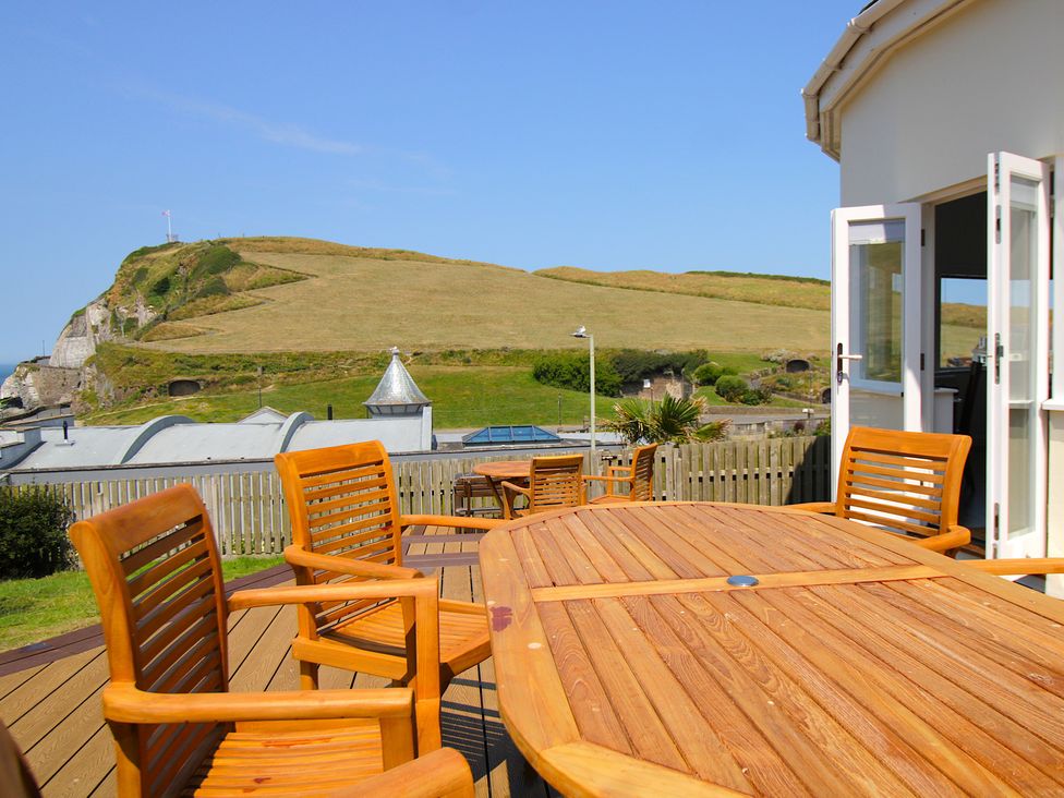 An outdoor patio with wooden furniture at 11 Cove View Apartments in Ilfracombe