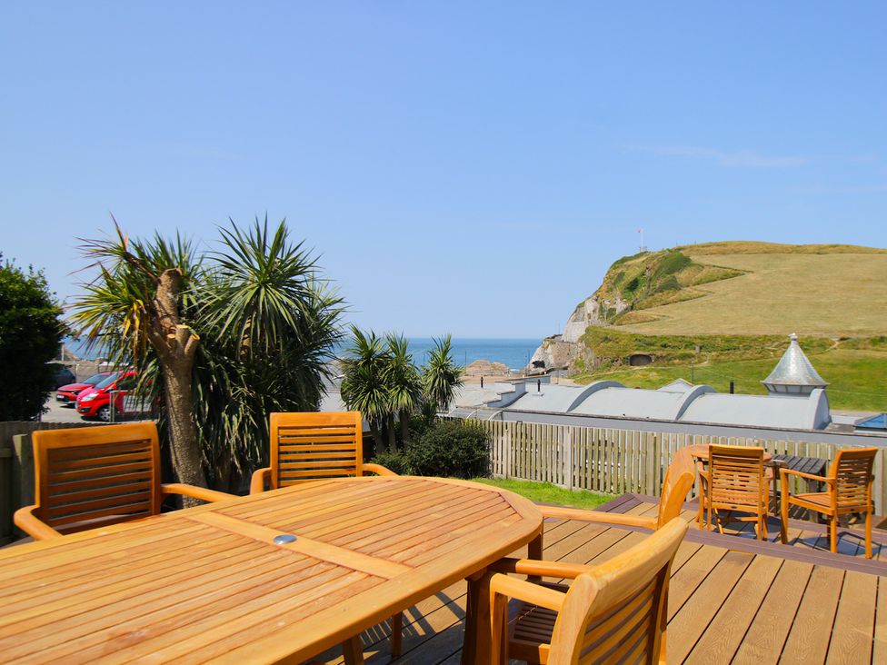 An outdoor area with a table and chairs overlooking the ocean at 11 Cove View Apartments Ilfracombe