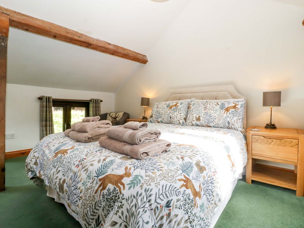 A bedroom with a bed and towels on top at Redstart Cottage in Kingsland