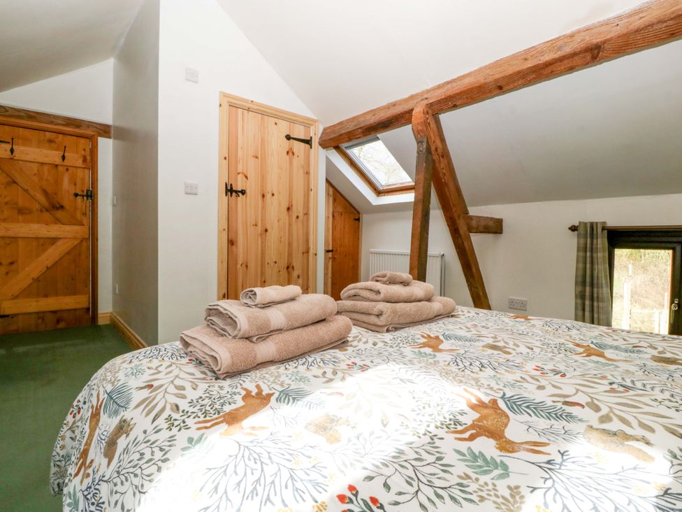 A bedroom with a bed and towels at Redstart Cottage in Kingsland