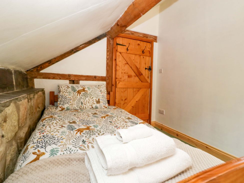 A bedroom with a single bed and a wooden door at Redstart Cottage in Kingsland