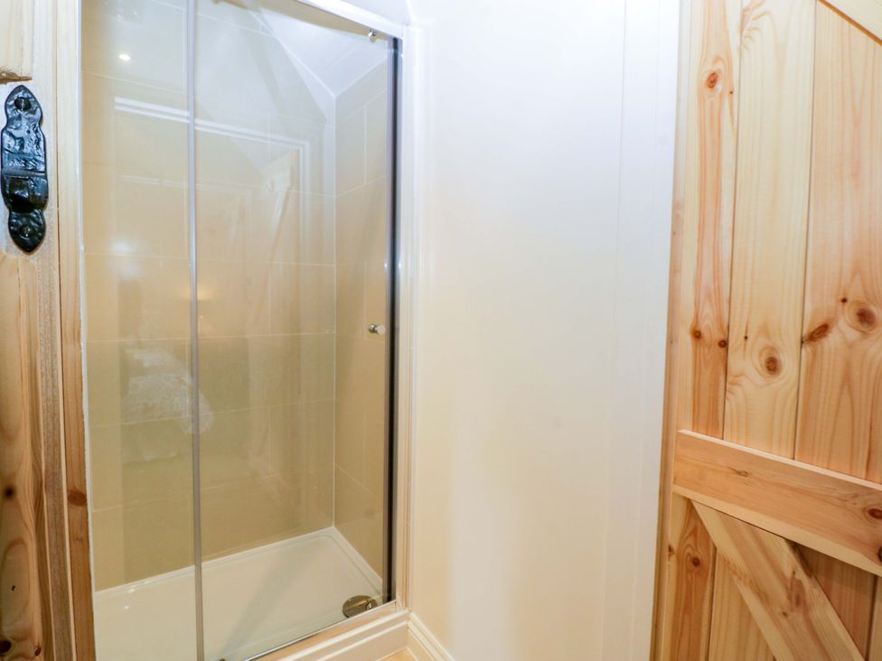 A shower area with a glass door at Redstart Cottage in Kingsland