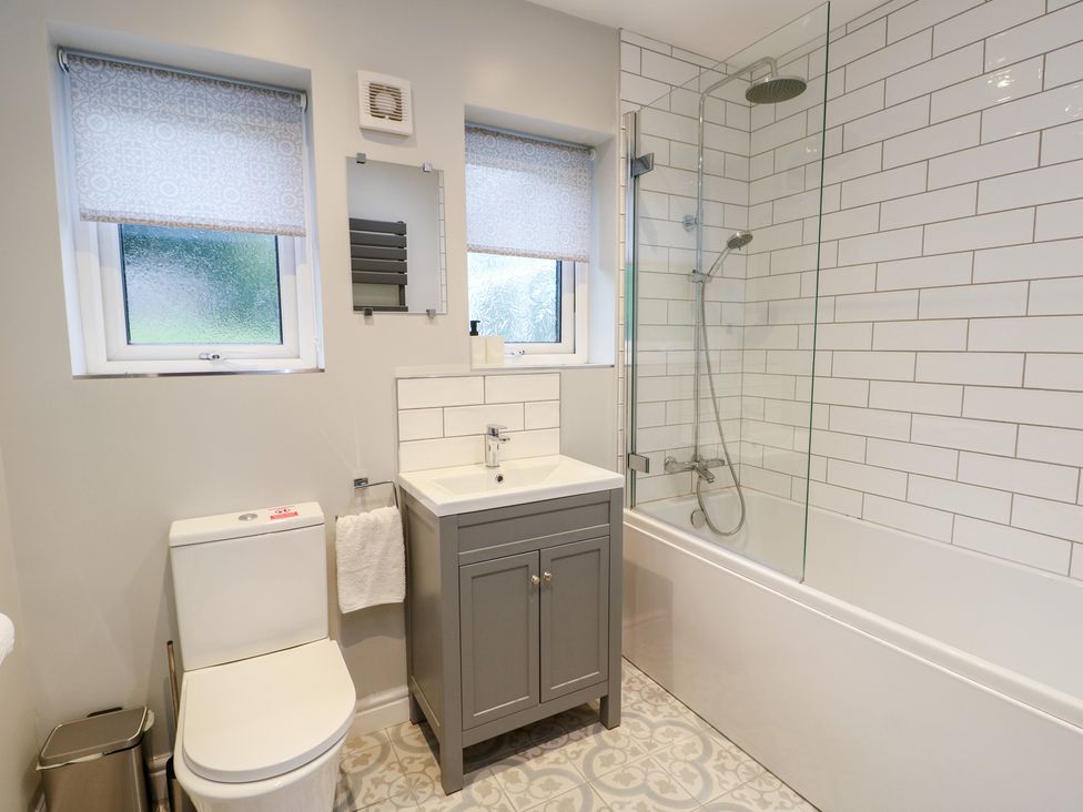 A bathroom with a sink, toilet, and shower at Treestumps in Benllech
