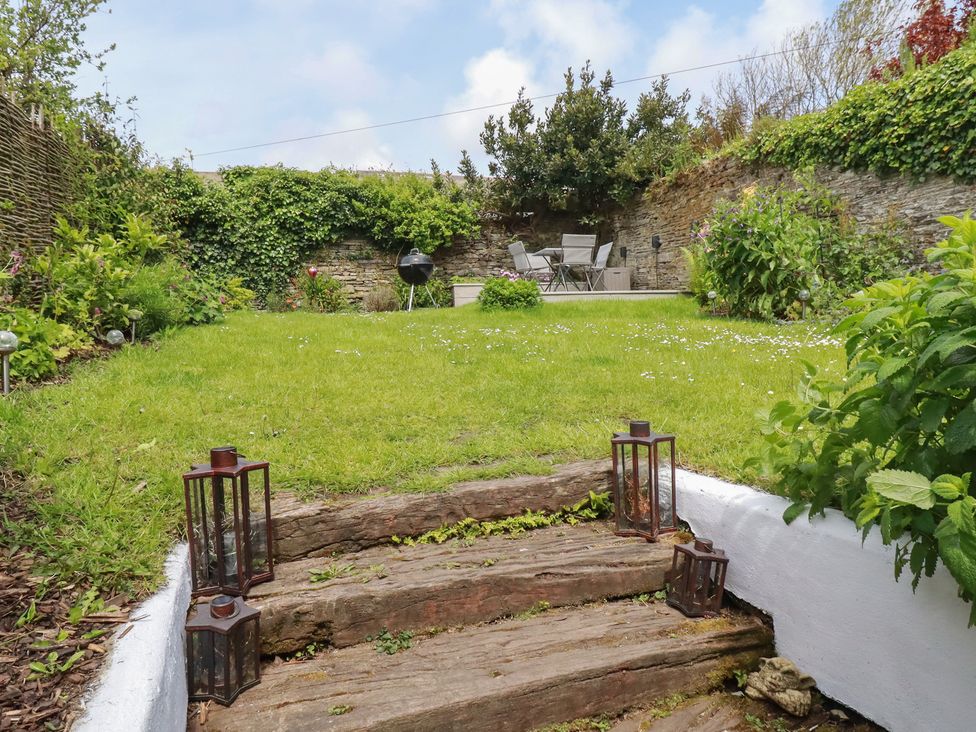 A garden with grass and seating area at Gwynn Cottage in St Mabyn