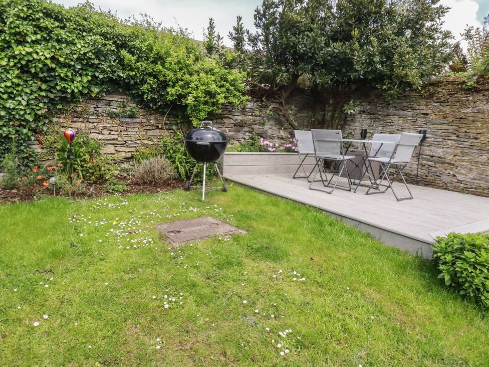 A garden with a barbecue grill and dining table at Gwynn Cottage in St Mabyn