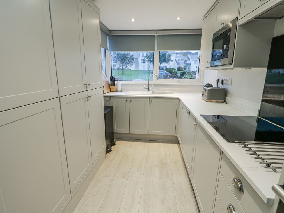 A kitchen with cabinets, sink, and appliances at White Sails Y Felinheli