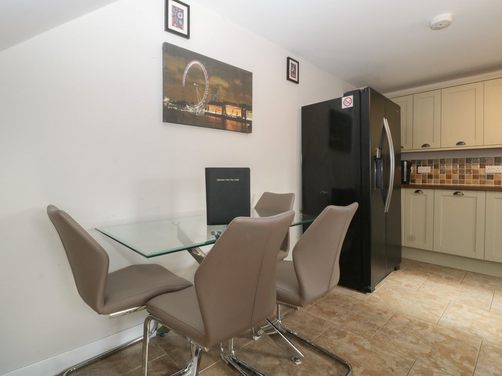 A kitchen with a dining table and refrigerator at Top Lodge in Llanvair-Discoed near Penhow