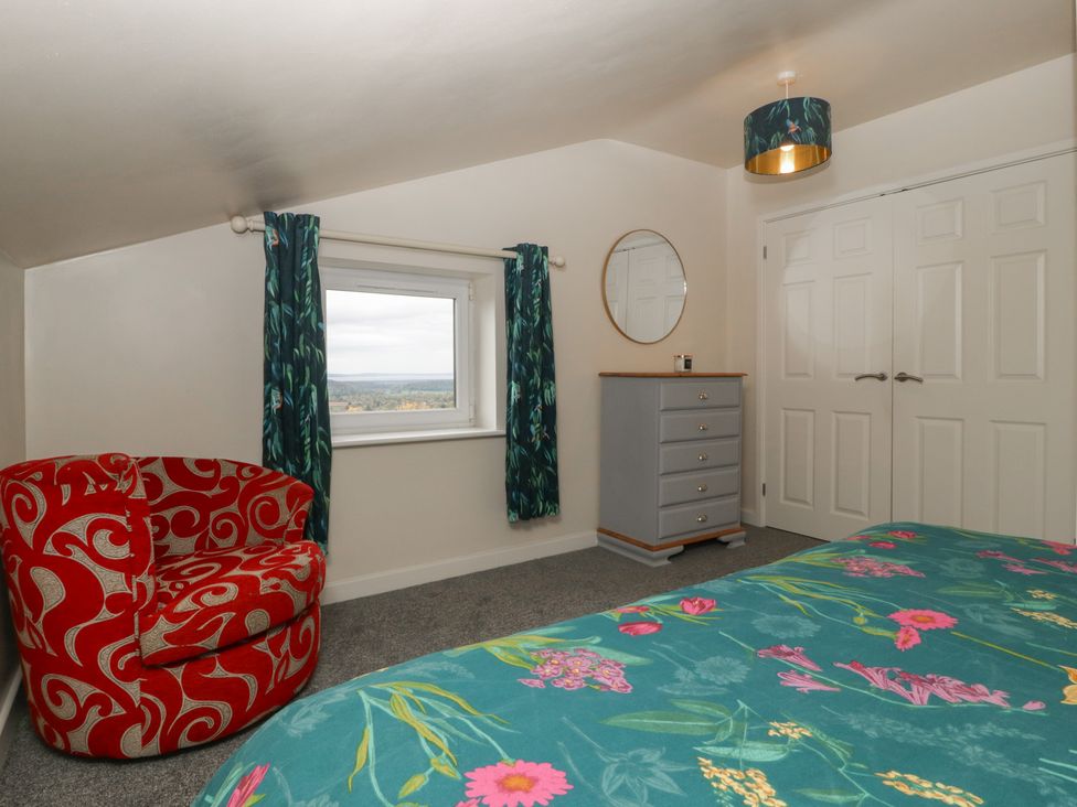 A bedroom with an armchair, window, and dressing table at Top Lodge Llanvair-Discoed near Penhow