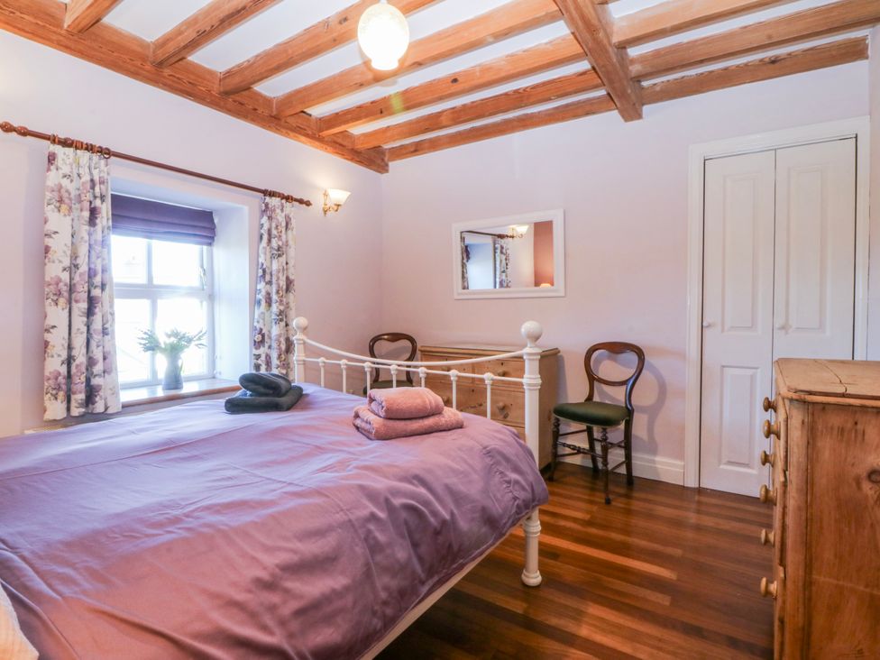 A bedroom with a bed, dresser and chair at Bronfa in Tregarth