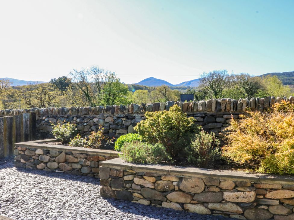 A garden with a stone wall and plants at Bronfa in Tregarth