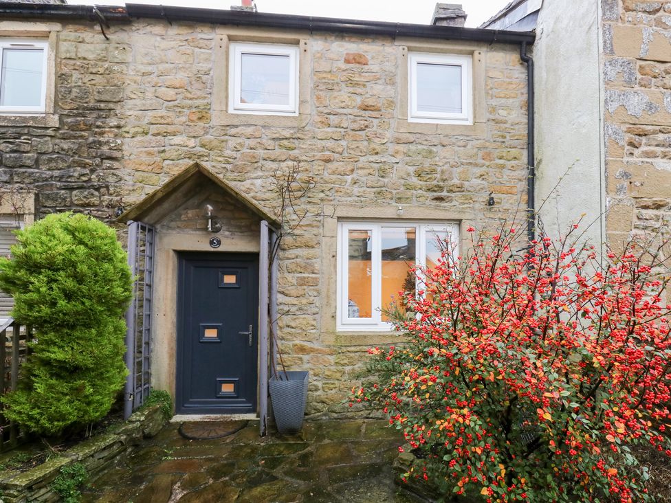 An entrance with a door and bush at Rosemount Cottage in Barnoldswick