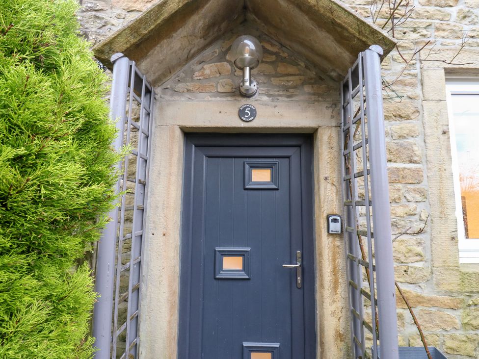 An entrance with a blue door and light fixture at Rosemount Cottage in Barnoldswick
