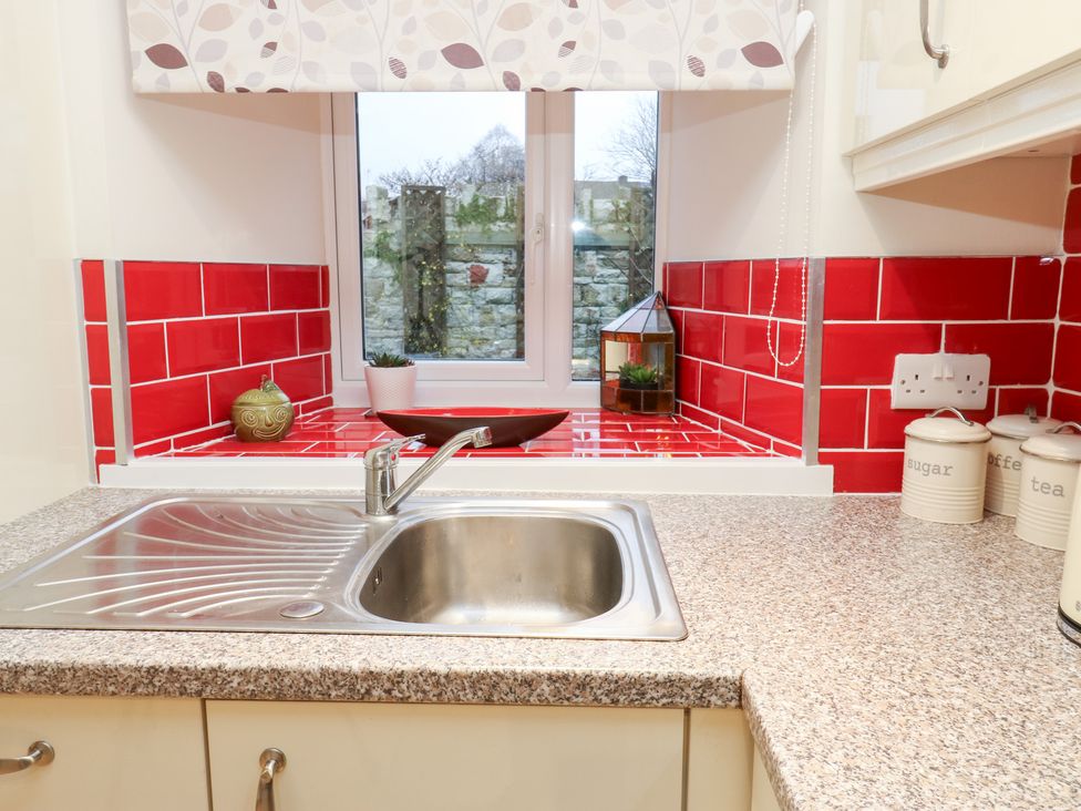 A kitchen with a sink and red tiles at Rosemount Cottage Barnoldswick