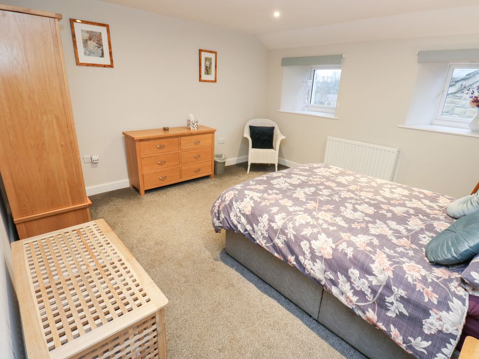 A bedroom with a bed and dresser at Rosemount Cottage in Barnoldswick