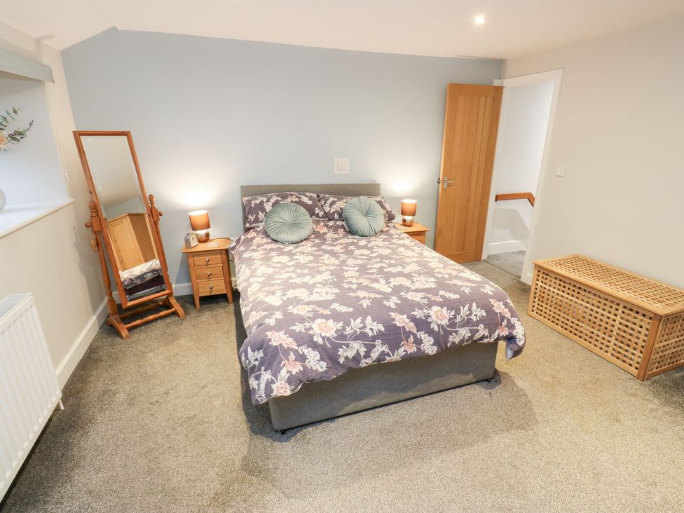 A bedroom with a bed and mirror at Rosemount Cottage Barnoldswick