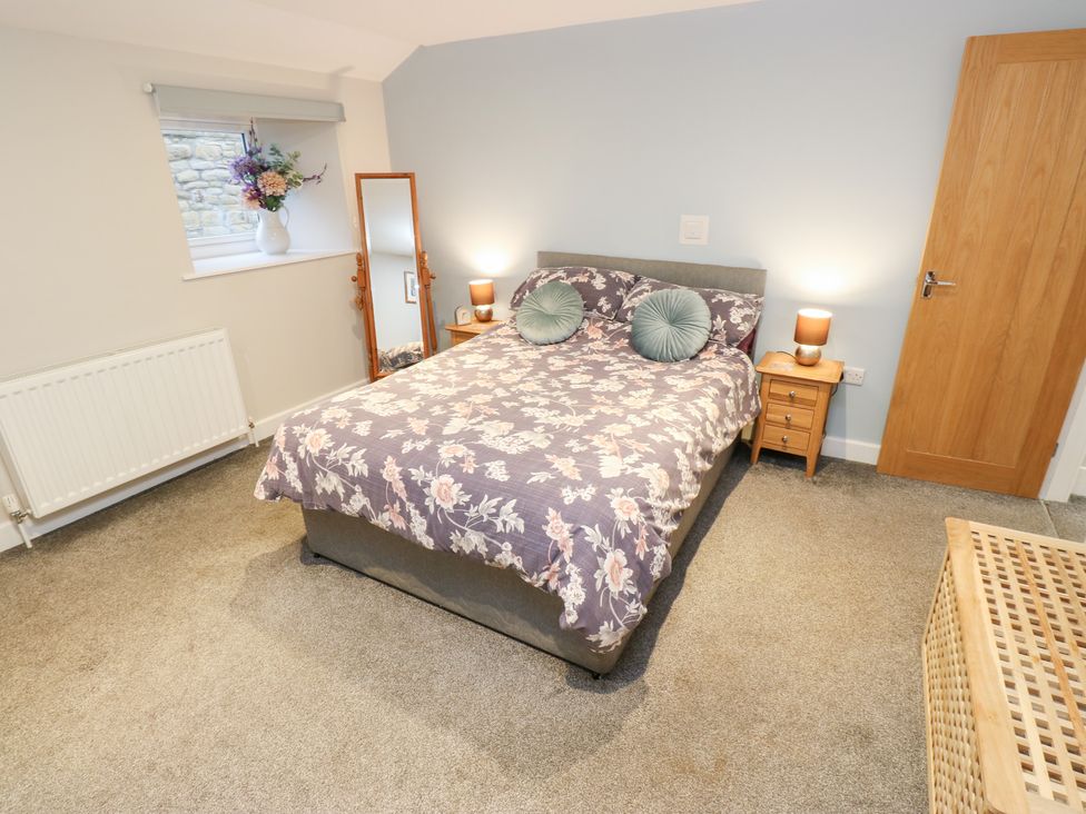 A bedroom with a bed and side table at Rosemount Cottage in Barnoldswick