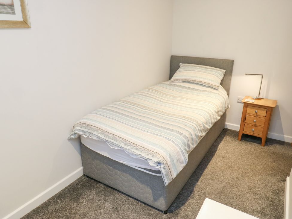 A single bed with bedside table and lamp at Rosemount Cottage Barnoldswick