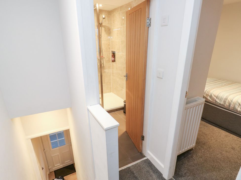 A hallway with steps leading down and a shower room at Rosemount Cottage Barnoldswick