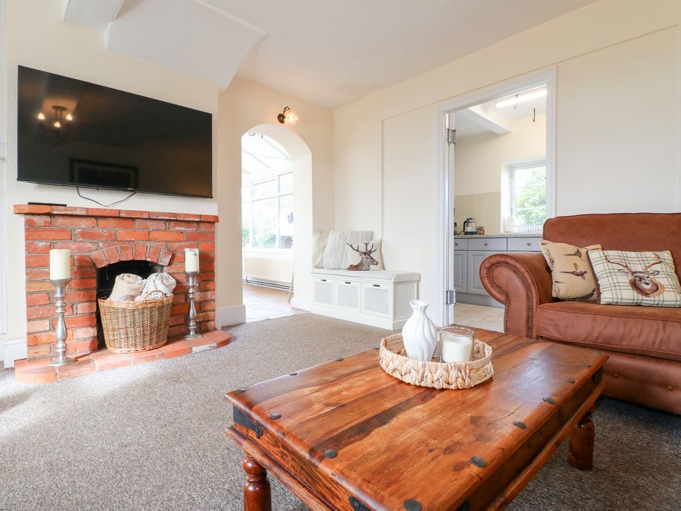 A living room with a television and brick fireplace at Far Coley Farm and Kilnhurst Log Cabin Great Haywood