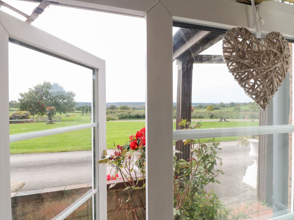 A window view with a heart decoration and flowers at Far Coley Farm and Kilnhurst Log Cabin in Great Haywood
