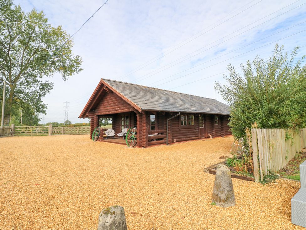 A log cabin with gravel driveway and trees at Far Coley Farm and Kilnhurst Log Cabin, Great Haywood