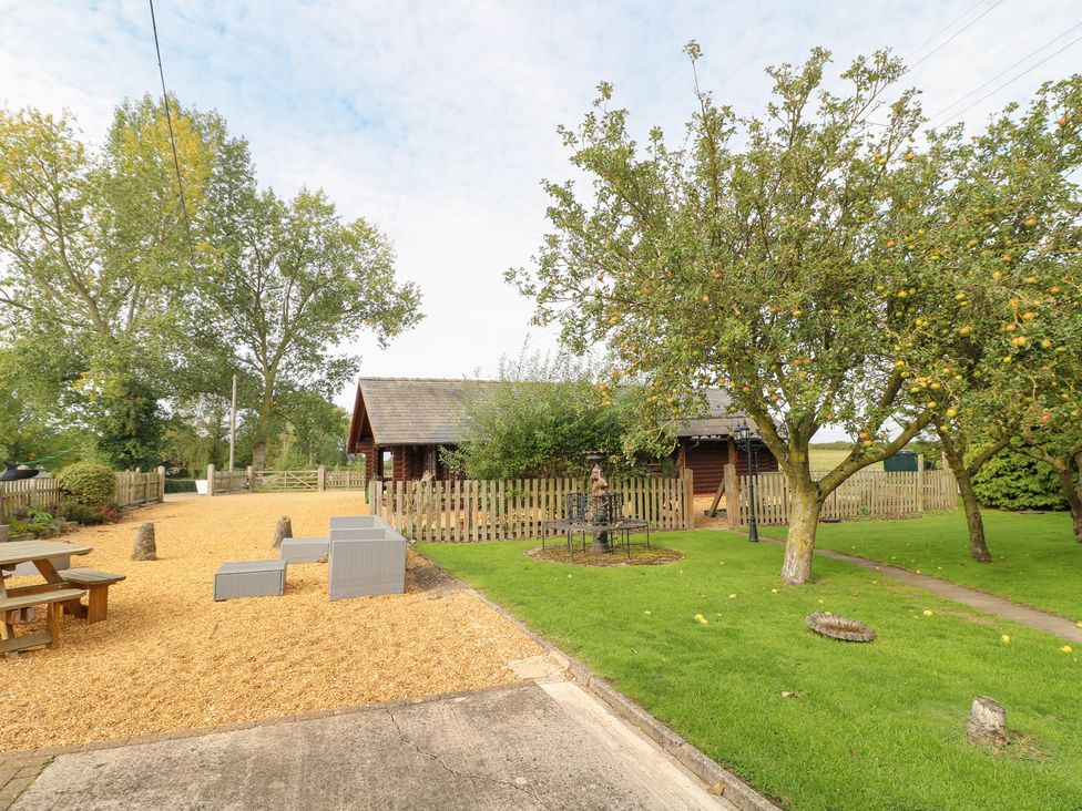 A garden with trees, a log cabin, and seating at Far Coley Farm and Kilnhurst Log Cabin in Great Haywood