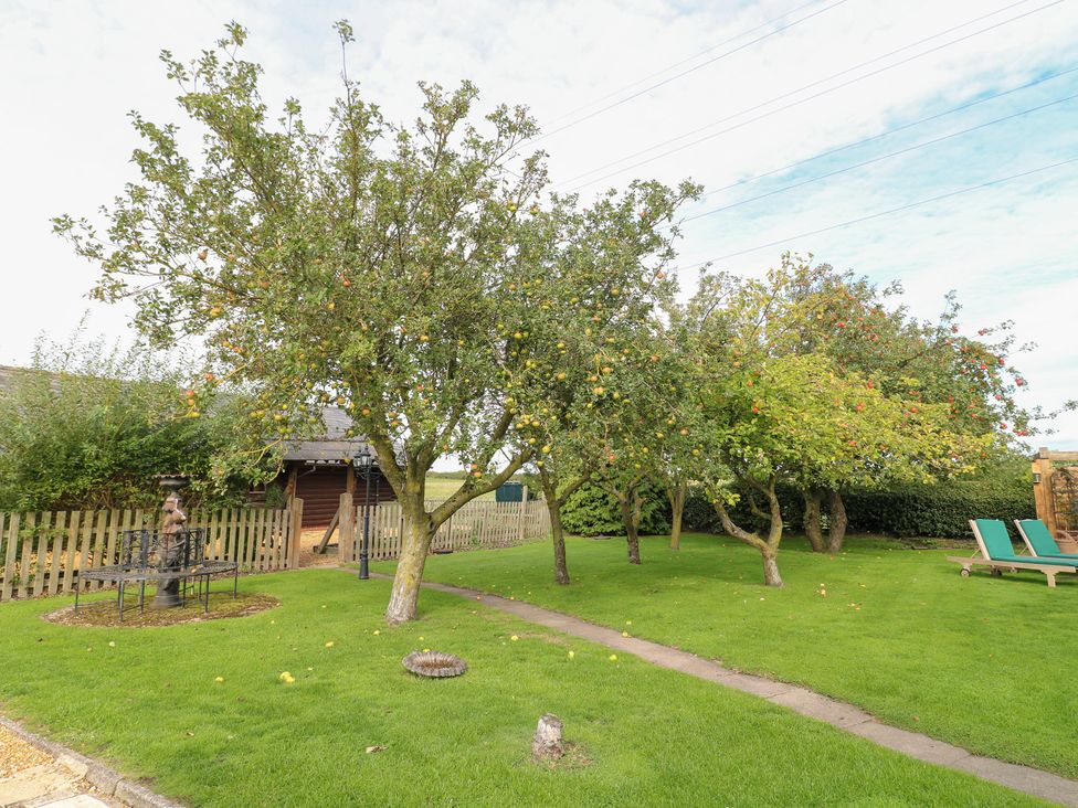 A garden with trees, a bench, and deck chairs at Far Coley Farm and Kilnhurst Log Cabin, Great Haywood