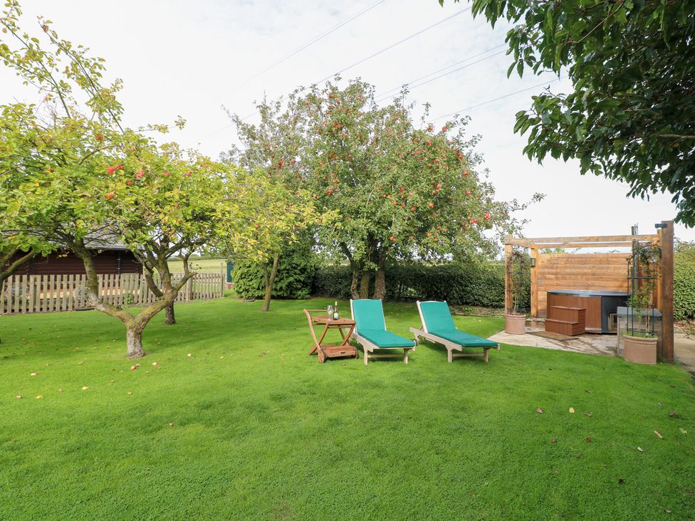 A garden with deck chairs and a hot tub at Far Coley Farm and Kilnhurst Log Cabin Great Haywood