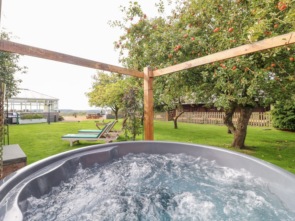 A hot tub with surrounding trees and deck chairs at Far Coley Farm and Kilnhurst Log Cabin Great Haywood
