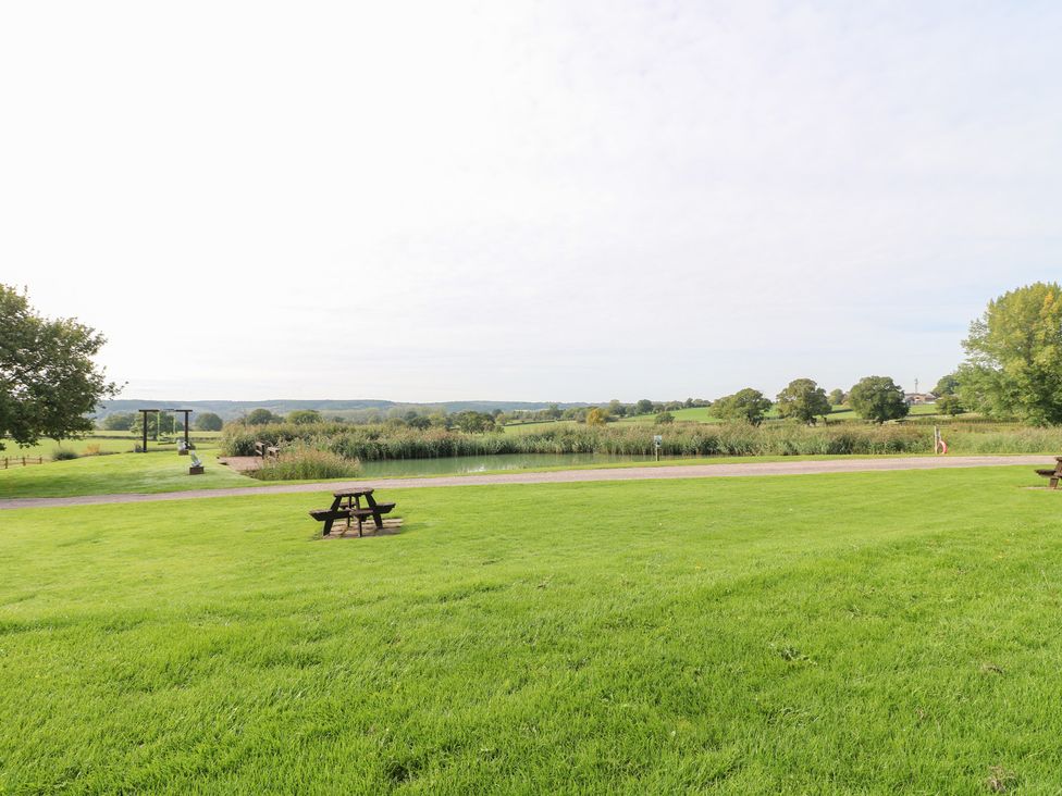 A garden with a pond and a bench at Far Coley Farm and Kilnhurst Log Cabin in Great Haywood